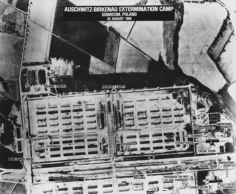 Declassified aerial reconnaissance photograph captioned “AUSCHWITZ-BIRKENAU EXTERMINATION CAMP, OSWIECIM, POLAND, 25 AUGUST 1944”, with the main guard house, guard towers, women’s camps, prisoner barracks, boxcars, gas chambers and crematoria annotated