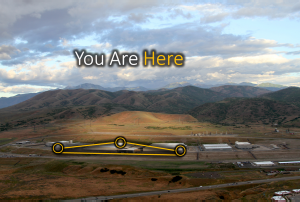 Aerial photograph of a large low-rise data-centre complex in a mountain valley, captioned “You Are Here”, with three of its buildings circled and joined by yellow network lines